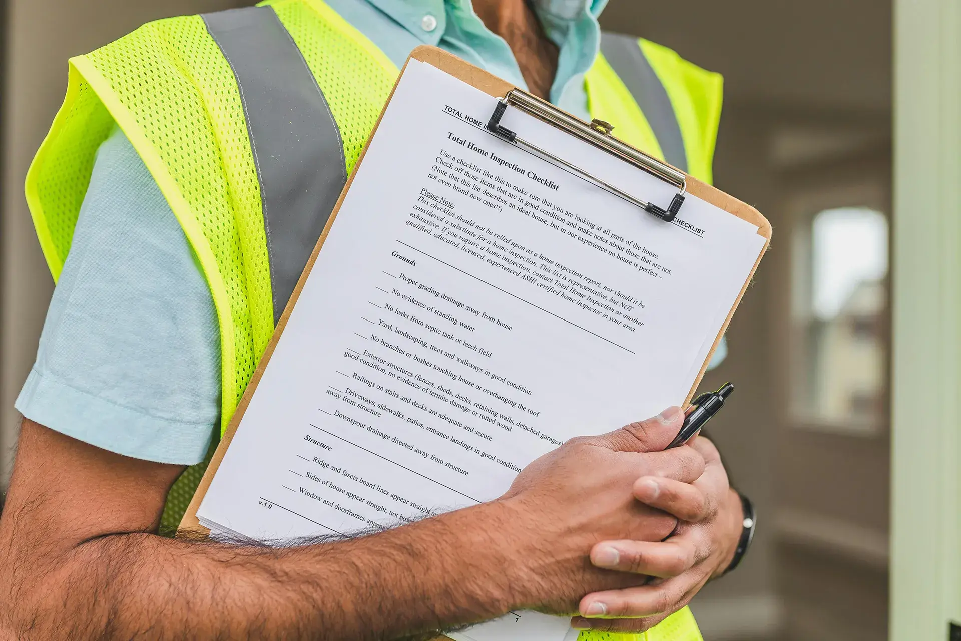 Close-up of a home inspector holding a clipboard with a home inspection checklist, symbolizing professional mold inspection and assessment.
